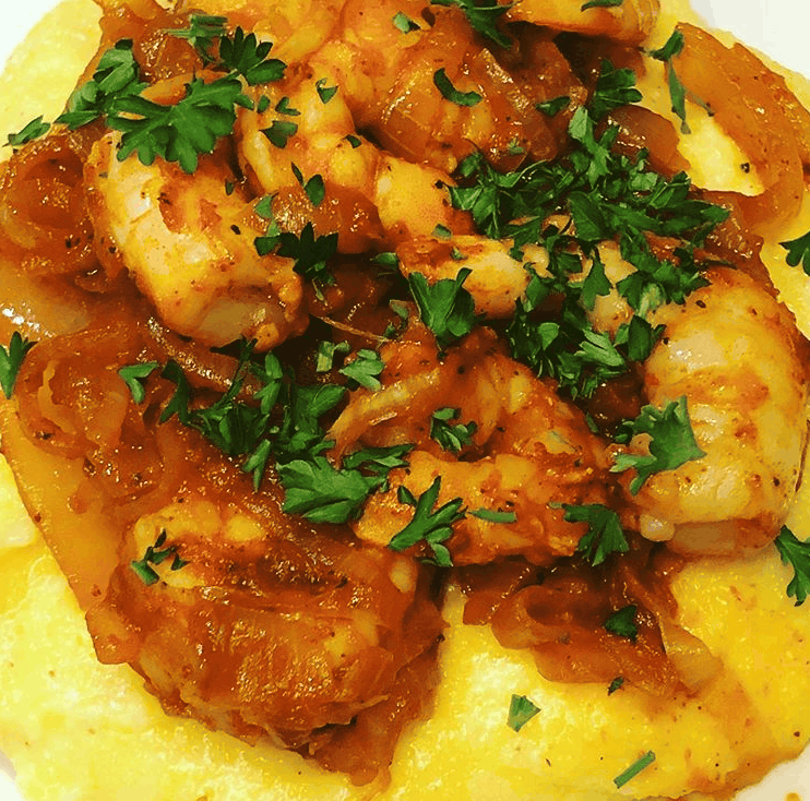 creamy yellow polenta topped with shrimp, peppers and onions sprinkled with parsley