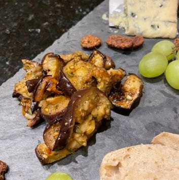pile of roasted and marinated eggplant on a cheese board