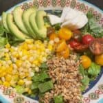 tomato and mozzarella salad topped with sunflower seeds, corn and avocado