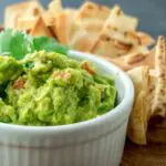 Picture of guacamole in white bowl with chips