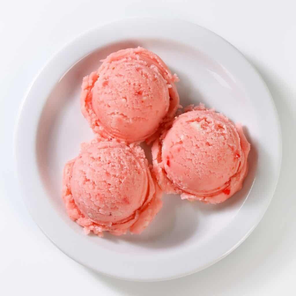 3 scoops of pink sorbet on a white plate