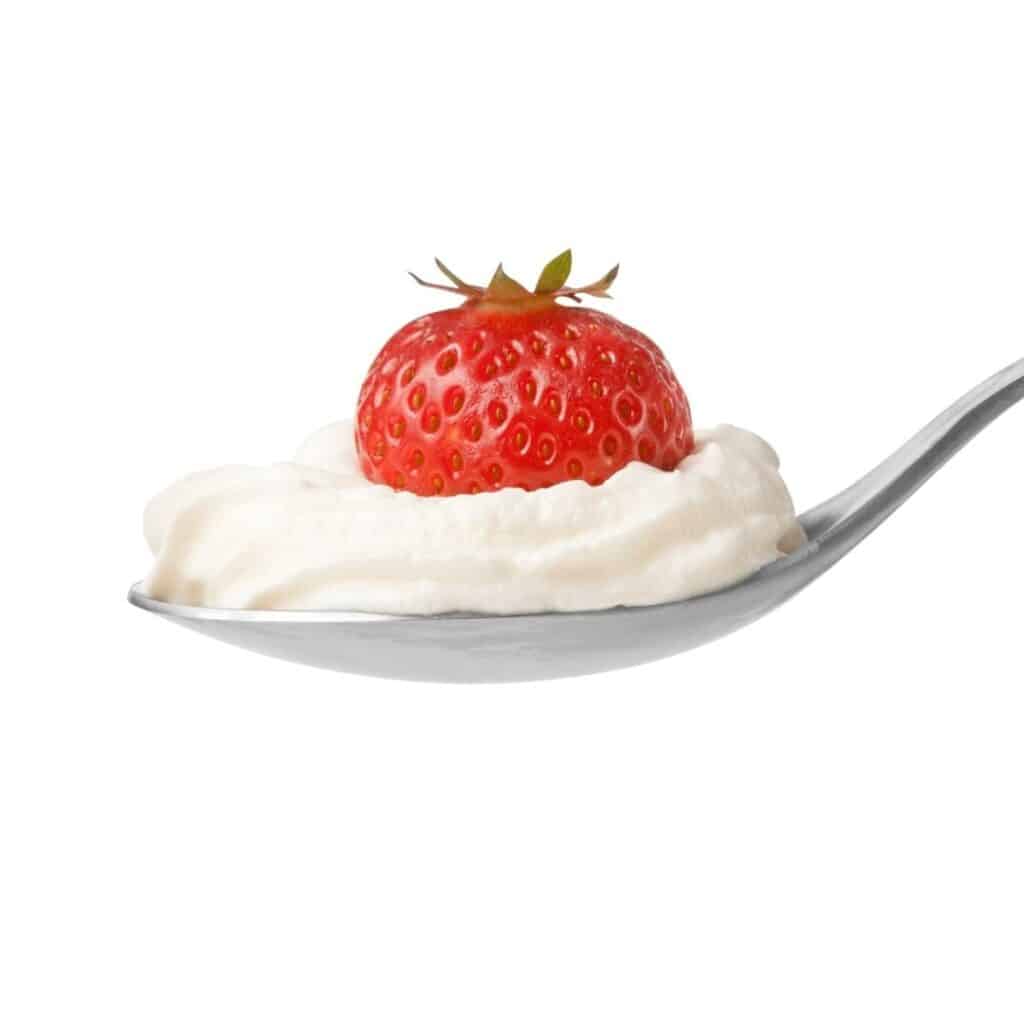 spoon with whipped cream and a strawberry