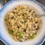 bowl of oatmeal that includes oats, apples, bananas, sliced almonds, almond milk, raisins, and pumpkin seeds