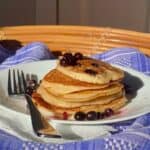 Image of stack of low sodium pancakes on blue tablecloth and fork with blueberries