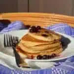 Image of stack of low sodium pancakes on blue tablecloth and fork with blueberries