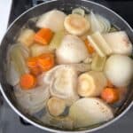 image of chicken soup that includes carrots, celery, white onion, and turnip